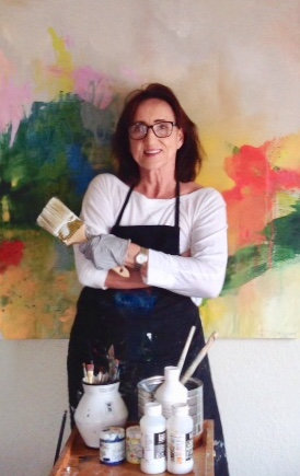 Portrait of Michele Zuzalek in an apron, holding a brush