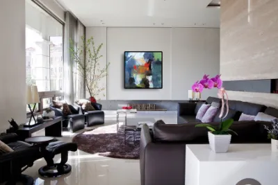 An abstract painting on the wall of a modern living room with dark sofas
