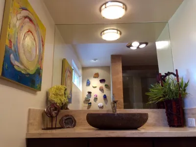 A swirling, colorful abstract hung beside a mirror above a stone basin